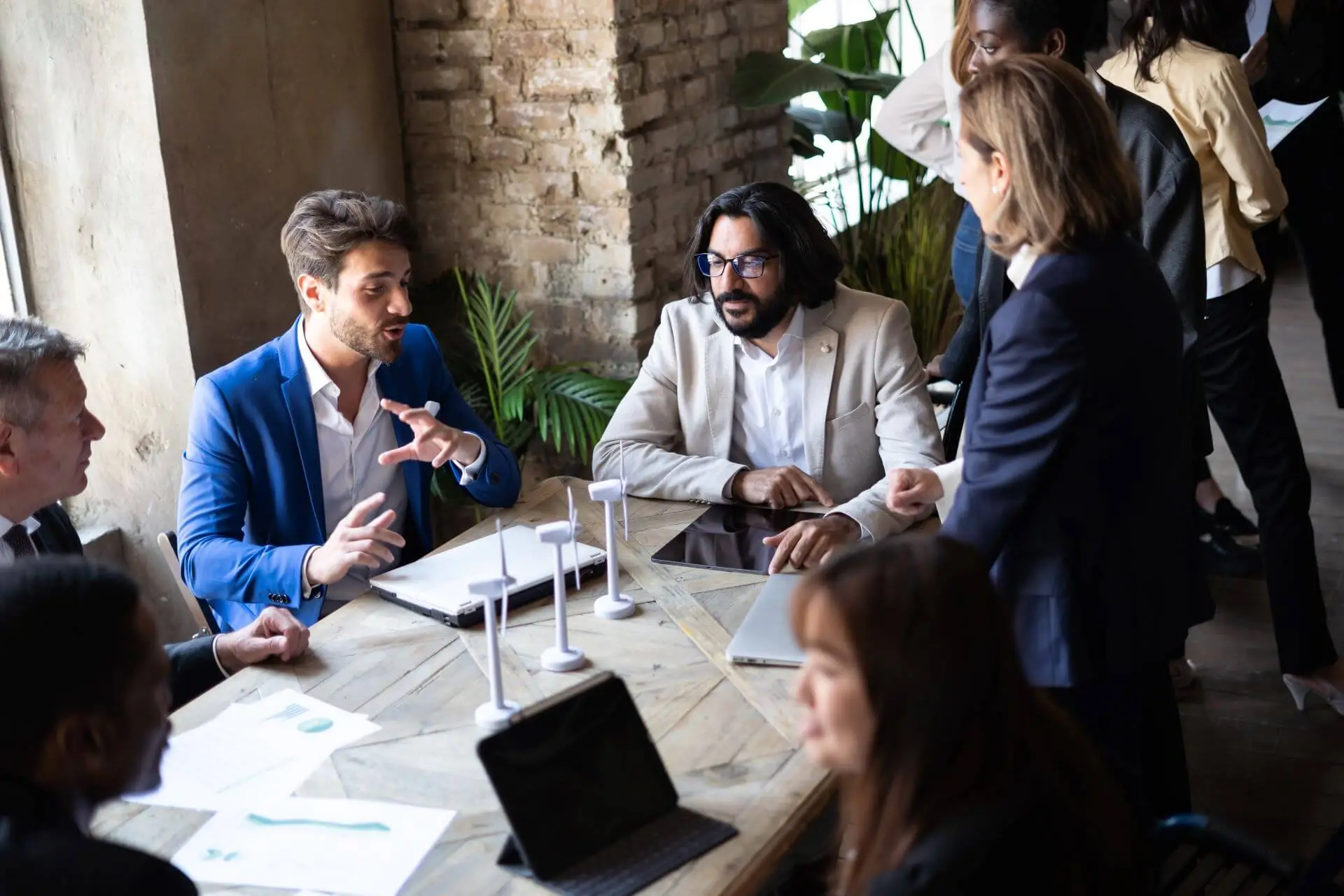Several people gather around a table, covered in papers.